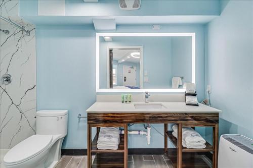 a bathroom with a sink and a toilet and a mirror at Seaside Boutique Hotel, Waves At Your Doorstep in Port Aransas