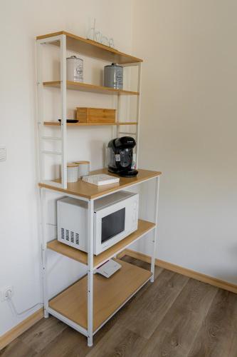 a book shelf with a microwave and a computer on it at Come4Stay Passau - GubyBlue & GubySun - 2 Wohnungen I bis zu 7 Gäste in Passau