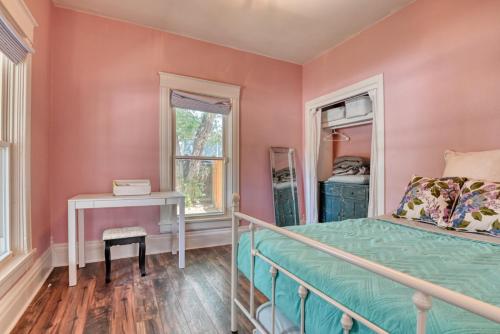 a bedroom with pink walls and a bed and a table at Colorado Columbine Cottage in Colorado Springs