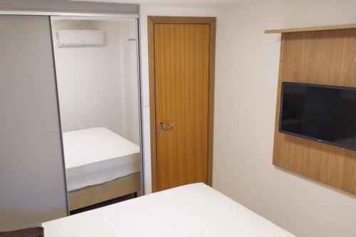 a small bedroom with a mirror and a television at Village 2 suítes beira mar Itacimirim in Camaçari