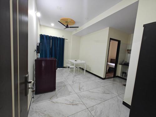 a room with a table and a blue curtain at Comfort Cove Apartments in Mysore