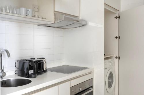 una pequeña cocina blanca con fregadero y fogones en Modern Heights 2BR apartment in Singapore!, en Singapur