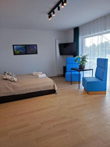 a bedroom with a bed and two blue chairs at Aquarius Stawy Walczewskiego 7 in Grodzisk Mazowiecki