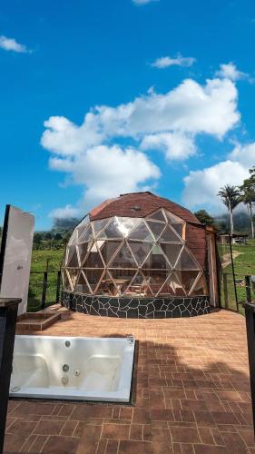 a large glass building with a tub in front of it at Glamping Reserva del Roble in La Vega