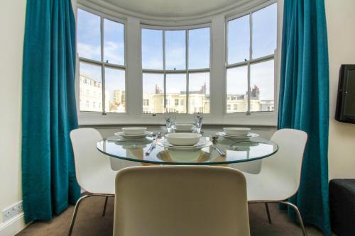 een eetkamer met een tafel en stoelen en een raam bij New Steine Apartment - Sea View - by Brighton Holiday Lets in Brighton & Hove