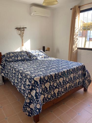 a bedroom with a bed with a blue comforter and a window at Medanos del Portal in Piriápolis