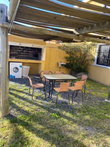 a table and chairs under a patio with a table and a washing machine at Medanos del Portal in Piriápolis