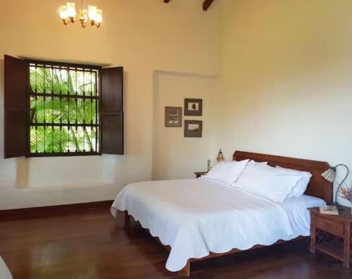 a bedroom with a white bed and a window at Hacienda la Romelia 