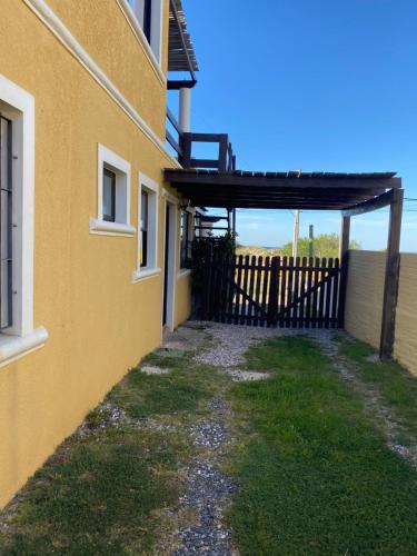 a yellow building with a gate and a fence at Medanos del Portal in Piriápolis