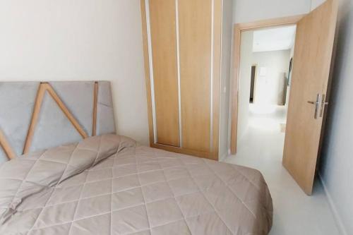 a bedroom with a bed and an open door at Appartement cosy proche Aéroport in Deroua