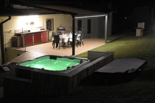 a hot tub in a backyard with a table and a kitchen at Casavacanzedezza in Montecalvo Versiggia