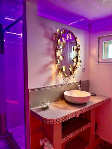 une salle de bain avec un lavabo et un miroir au mur dans l'établissement Espace détente jacuzzi sauna, à Gagny