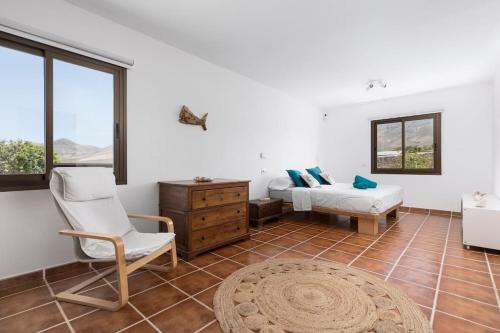 a bedroom with a bed and a chair and a table at Casa Marisa with Heated Pool & Garden in Tindaya