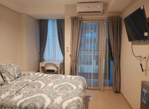 Cette chambre dispose d'un lit, d'une télévision et de fenêtres. dans l'établissement APART BY ANOM, à Bandung