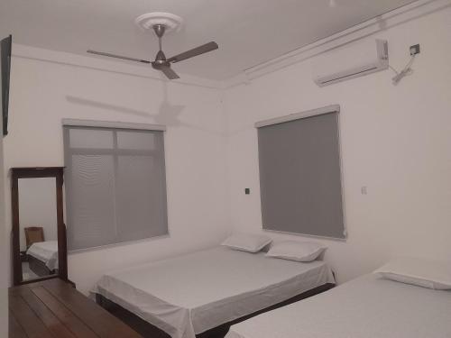 a white room with two beds and a ceiling fan at LIZI VILLA in Beruwala