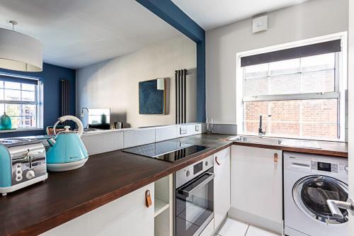 a kitchen with a sink and a washing machine at Beautiful Aldgate Apartment in London