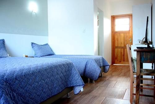 Pousada Costa e Mar في Tavares: غرفة نوم بسريرين مع شراشف زرقاء وارضية خشبية