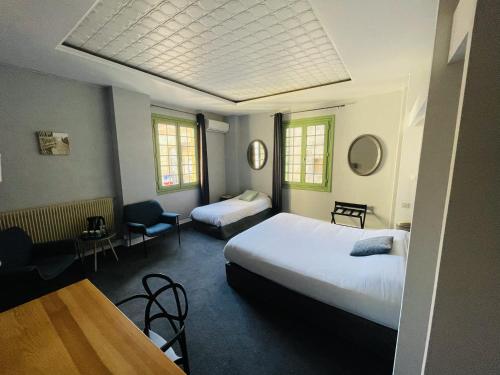 a hotel room with two beds and a table and chairs at Hôtel De La Loge in Perpignan