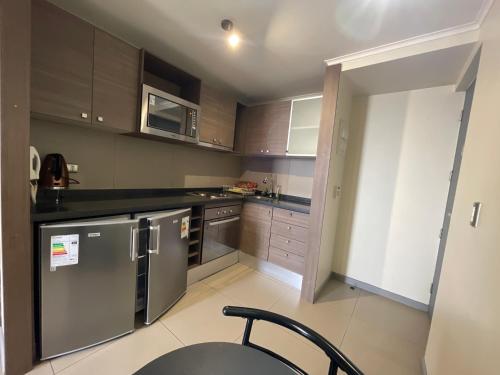 a kitchen with stainless steel appliances and wooden cabinets at Yolier Suites in Santiago