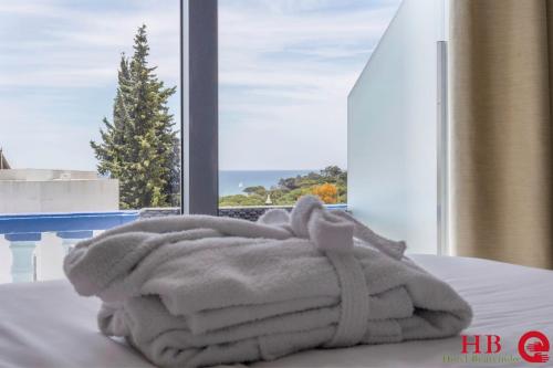 a pile of towels sitting on a bed in front of a window at Urban Hotel Santa Eulalia in Albufeira