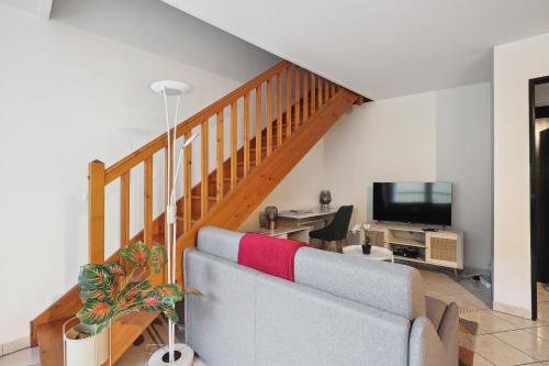 a living room with a staircase with a couch and a television at Chic apart duplex with parking in Palaiseau