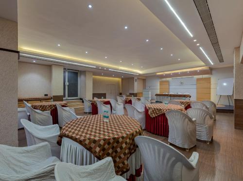 un salón de banquetes con mesas, sillas blancas y una pantalla en Hotel Pratham, en Solapur