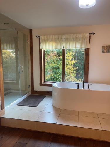 a large bathroom with a tub and a window at Chalet Spa Alizee Mont-Blanc in Saint-Faustin