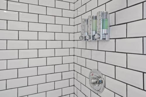 uma casa de banho em azulejos brancos com um chuveiro e um dispensador de sabonete em BRAND NEW, Private Parking, Stylish 3bedroom house em Pittsburgh