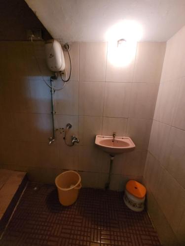 a bathroom with a sink and a toilet and a light at JAI MALHAR LODGE in Pune
