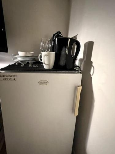 a white refrigerator with dishes and utensils on top of it at Cozy Private Room 4 on a Busy Persian Restaurant in Eindhoven