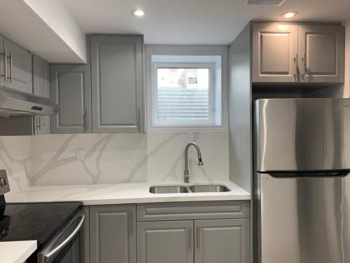 a kitchen with a sink and a refrigerator at Adorable 2-Bedroom Basement with Sep Entrance in Ajax