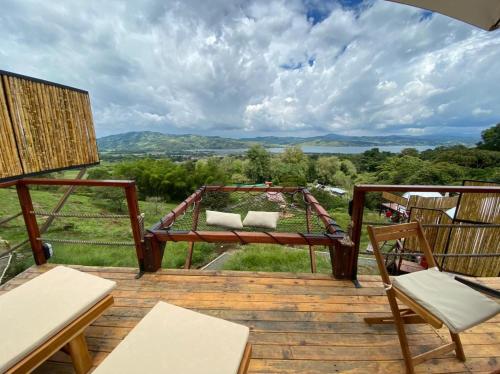 a patio with chairs and a swing on a wooden deck at MACA GLAMPING in Calima