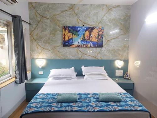 a bedroom with a bed with a painting on the wall at Beautiful 1 BHK With Pool Wi-Fi Cooking Gas Gym Caretakers in Old Goa