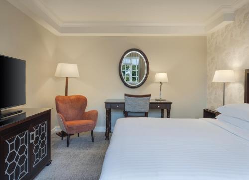 a hotel room with a bed and a desk and a tv at Delta Hotels by Marriott St Pierre Country Club in Chepstow