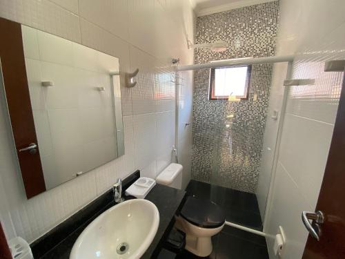 a bathroom with a sink and a toilet and a mirror at Residencial Porto di Lázaro in Ubatuba