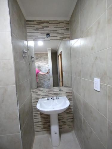 ein Badezimmer mit einem Waschbecken und einer Person im Spiegel in der Unterkunft La Baileyana. in Pringles