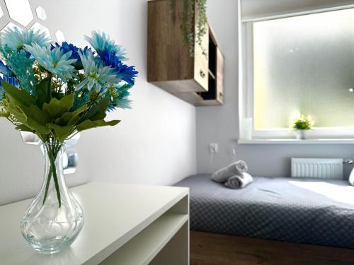a vase of blue flowers on a counter in a room at MMRent Citrus Room in Gdańsk
