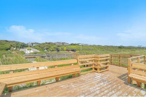 a wooden deck with two benches and a view of the ocean at Sea-Nic View in Caswell Beach