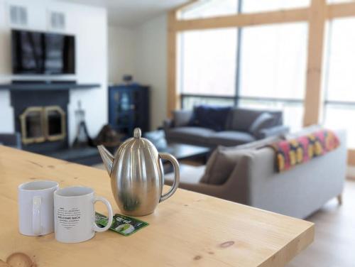 una mesa de madera con dos tazas de café encima en Stunning lakefront 4 season cottage in PEC en Bongards