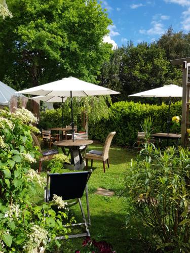 a garden with a table and chairs and umbrellas at Chambres d'hôtes couleur bassin d'Arcachon in Andernos-les-Bains