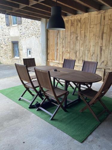 une table et des chaises en bois sur un tapis vert dans l'établissement Les Séchoirs piscine et spa privatifs, à Saint-Romans