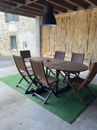 een houten tafel en stoelen op een groen tapijt bij Les Séchoirs piscine et spa privatifs in Saint-Romans
