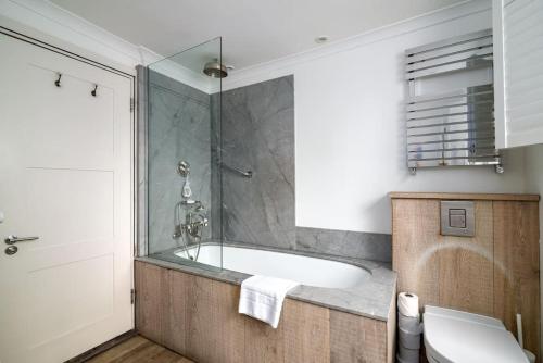 a bathroom with a bath tub and a toilet at Elegant Apartment near Portobello Road Market in London