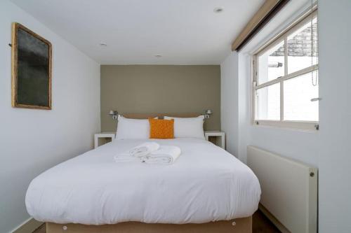 Cama blanca en habitación con ventana en Elegant Apartment near Portobello Road Market, en Londres