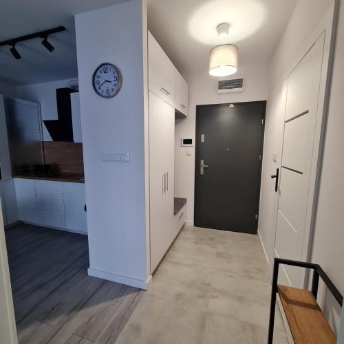 a hallway with a clock on a wall and a door at Green De Lux Apartament Dziwnów in Dziwnów