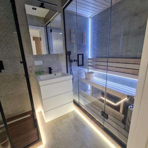 een badkamer met een wastafel en een glazen douche bij Green De Lux Apartament Dziwnów in Dziwnów