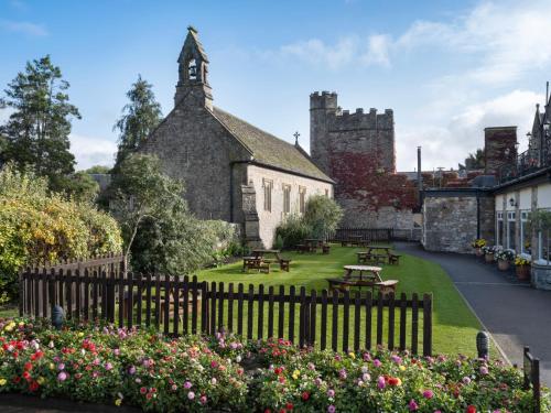 an old building with a yard with benches and flowers at Delta Hotels by Marriott St Pierre Country Club in Chepstow