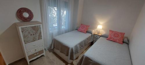 a small room with two beds and a mirror at Apartamento La Porteña, 200 ms de playa Victoria in Cádiz