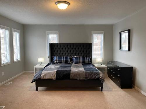 a bedroom with a bed and two tables and windows at Adorable Ajax House for Rent in Ajax