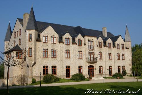 a large stone building with a black roof at Hotel Hinterland in Alveringem
